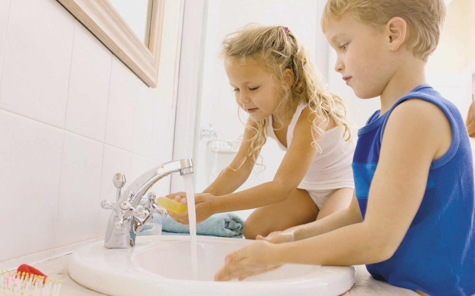 Otroci si umivajo roke z milom pod tekočo vodo