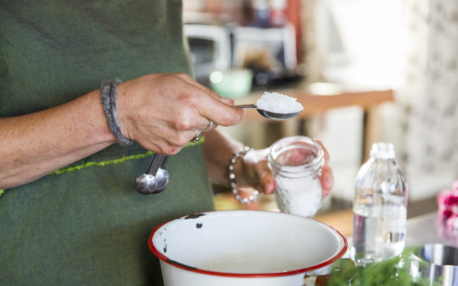 Ženska stresa veliko žlico soli v posodo v kuhinji