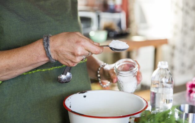 Ženska stresa veliko žlico soli v posodo v kuhinji