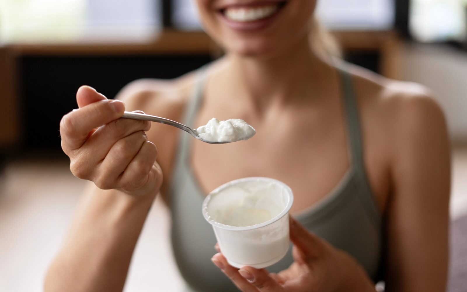 Ženska po vadbi je beljakovinsko bogato malico - jogurt.