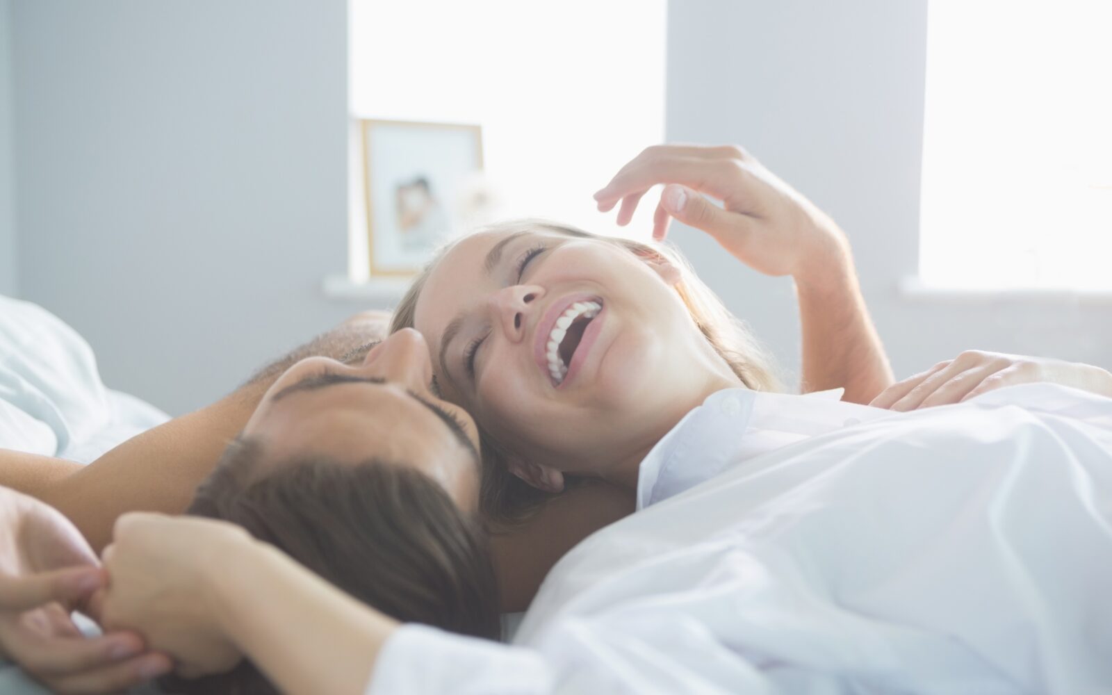 Mlad par leži v postelji - oba sta zadovoljna in se smejita