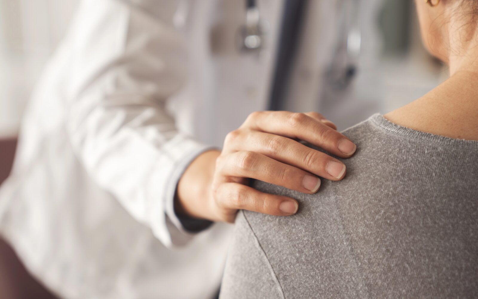 Zdravnik ima roko na rami bolnice, v znak sočutja, empatije