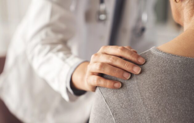 Zdravnik ima roko na rami bolnice, v znak sočutja, empatije