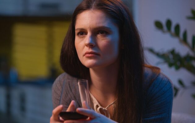 Ženska s kozarcem vina v roki skuša umiriti stres in napetost.