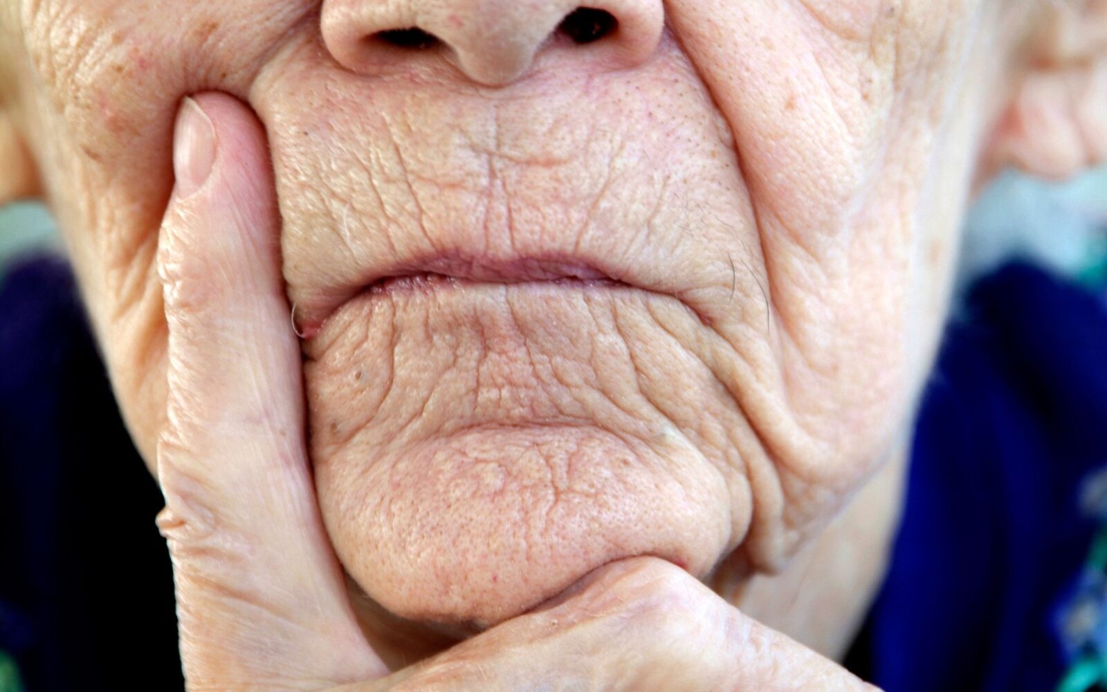 Starejša ženska z bolečim izrazom na obrazu, znak bolečine pri demenci