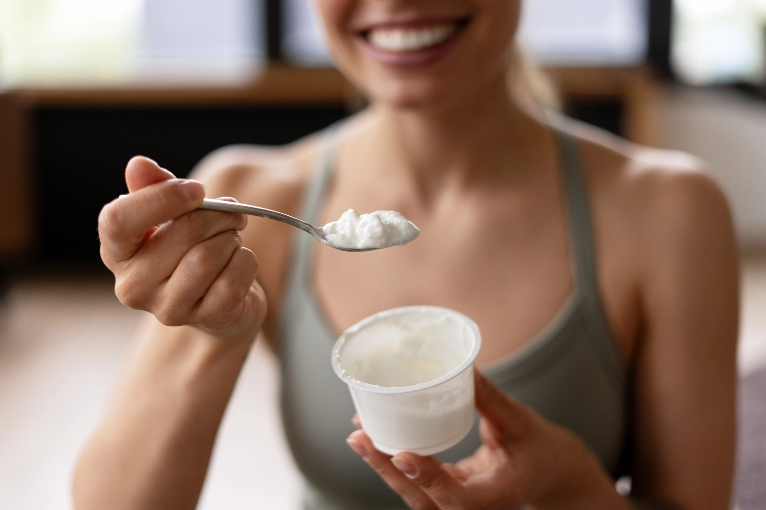 Mlada ženska ima po vadbi v roki jogurt za povrnitev energije.