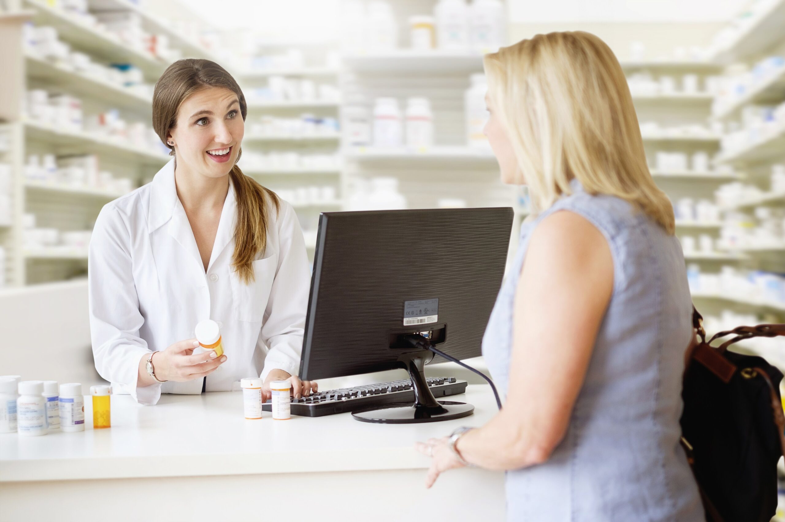 Potrošnica se v lekarni pogovarja s farmacevtko, ki ji svetuje glede izbire zdravil in prehranskih dopolnil