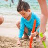 Otrok se igra na plaži in je zaščiten pred UV sevanjem z majico