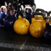 Ročne uteži (kettlebelli) različnih tež in barv v fitnesu.