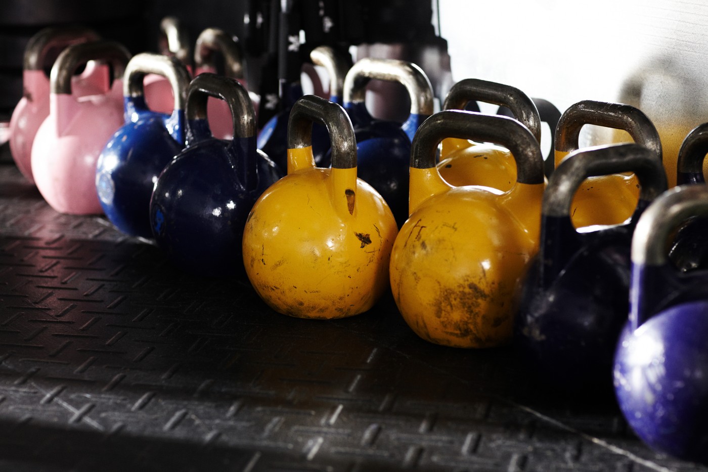 Ročne uteži (kettlebelli) različnih tež in barv v fitnesu.