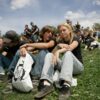 Mladi na poletnem festivalu sedijo na travi