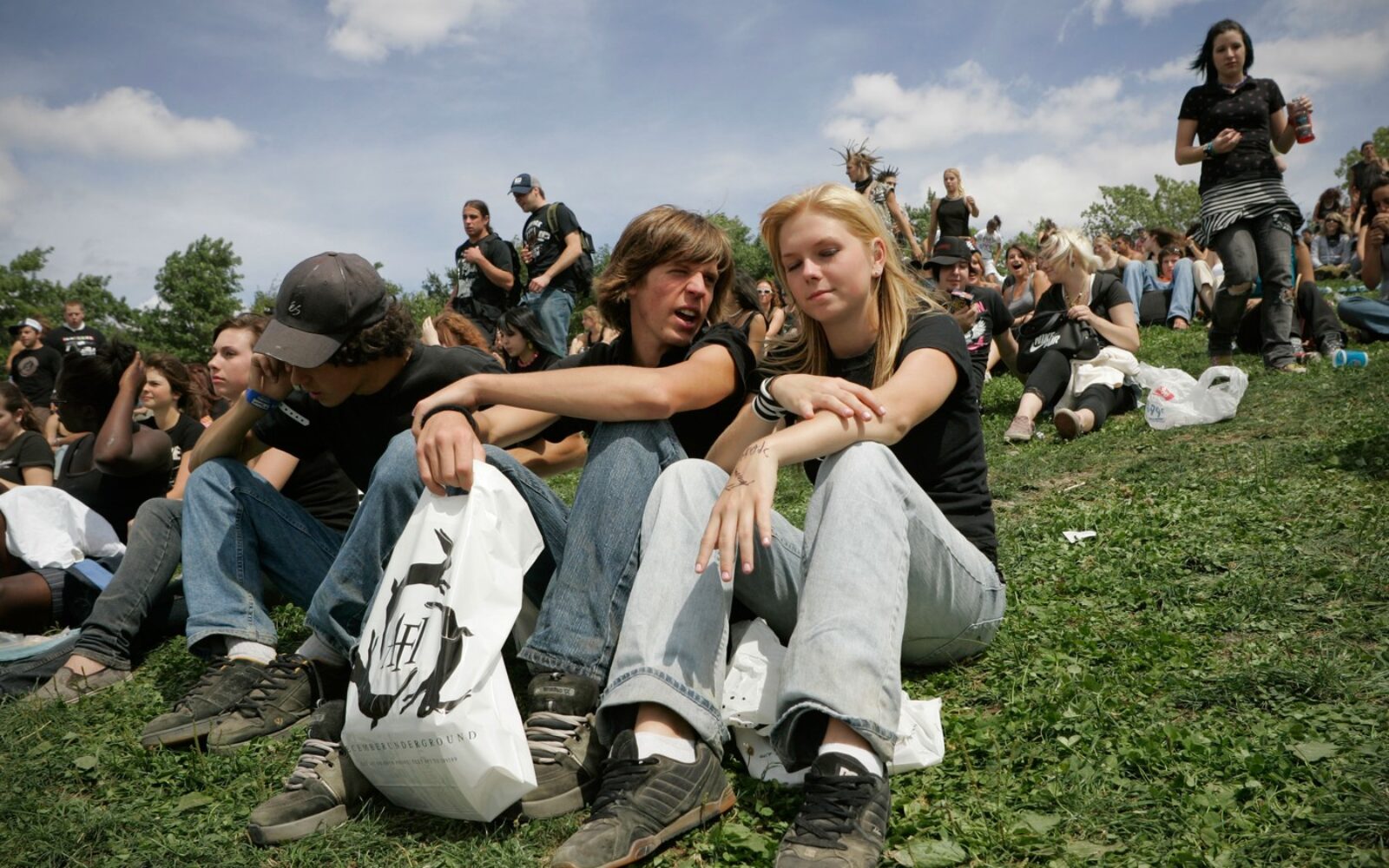 Mladi na poletnem festivalu sedijo na travi