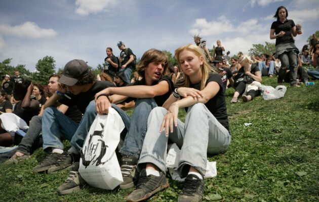 Mladi na poletnem festivalu sedijo na travi