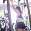 Ženska izvaja trening za moč v fitnesu na napravi z utežmi.