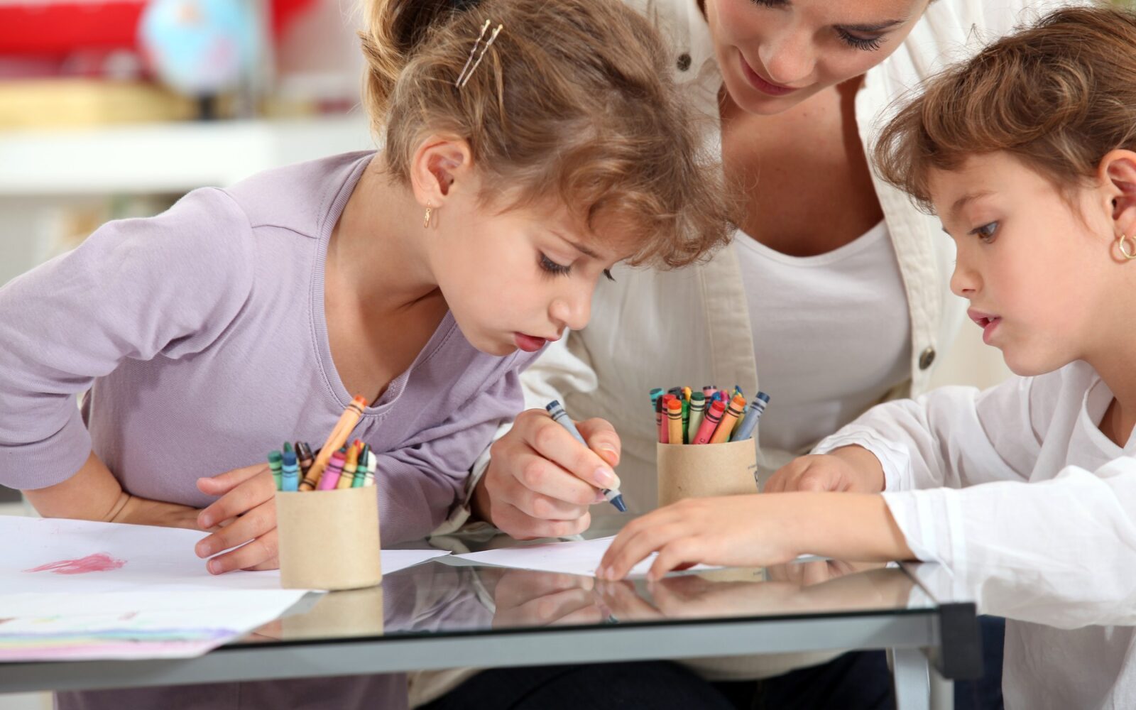 Mama opazuje svoja dva otroka medtem ko barvata pobarvanko