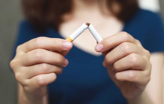 Oseba v rokah lomi cigareto kot simbol opustitve kajenja.