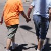Starejši par se drži za roke in se sprejhaja na topel sončni dan
