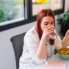 Rdečelasa ženska se prehranjuje in med obrokom pije vodo