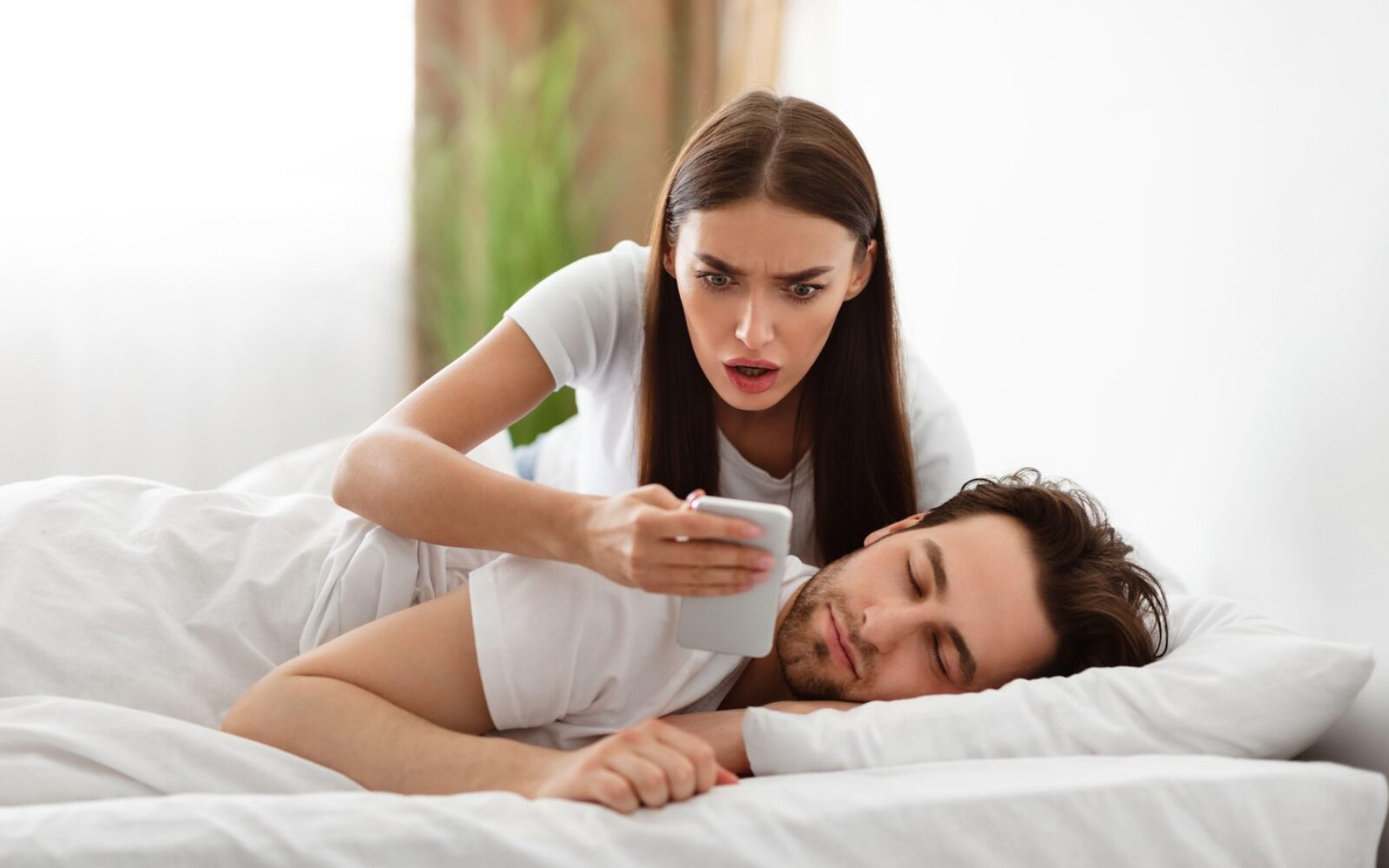 Ženska z zaskrbljenim izrazom gleda v telefon ob partnerju