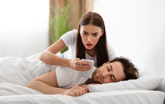 Ženska z zaskrbljenim izrazom gleda v telefon ob partnerju