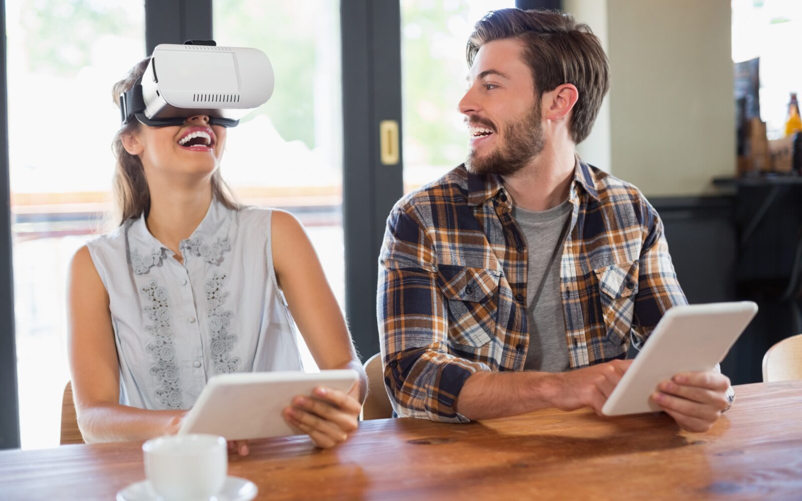 Mlad par sedi za mizo in se zabava s tablicami in VR očali - tehnologija nam omogoča, da nam nikoli več ni dolgčas.