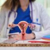 Zdravnica ginekologinja sedi za mizo in se s pomočjo anatomskega modela ženskega reproduktivnega sistema pogovarja o ženski sterilizaciji.
