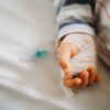 bližnji posnetek dojenčkove roke, ki ima nastavljen kanalček v roki - je hospitaliziran