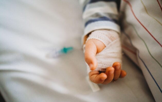 bližnji posnetek dojenčkove roke, ki ima nastavljen kanalček v roki - je hospitaliziran