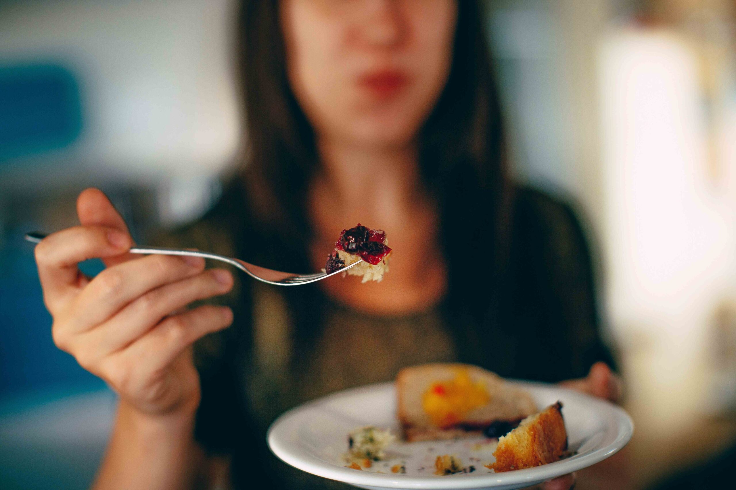 Ženska je nekaj sladkega, v ospredju fotografije je sladica na vilici