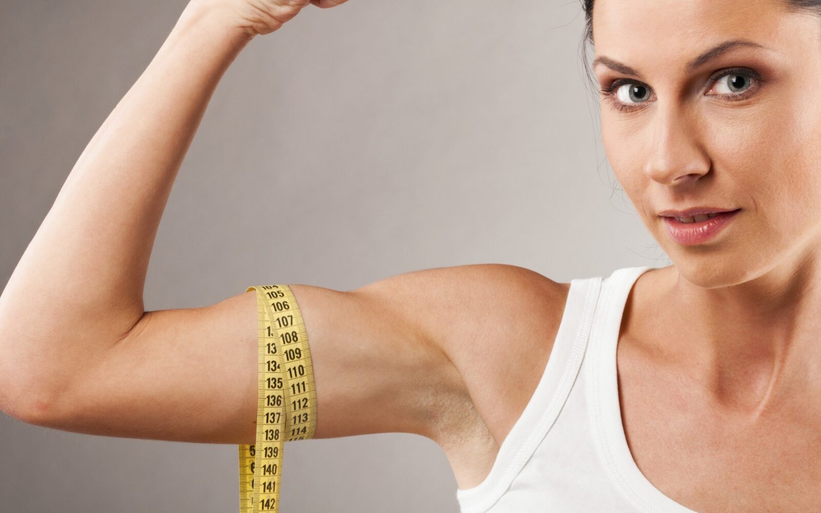 Ženska kaže svoje bicepse, okoli katerih ima meter