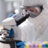 Raziskovalec v zaščitni protikužni obleki med laboratorijskim delom pri preučevanju povzročiteljev kuge