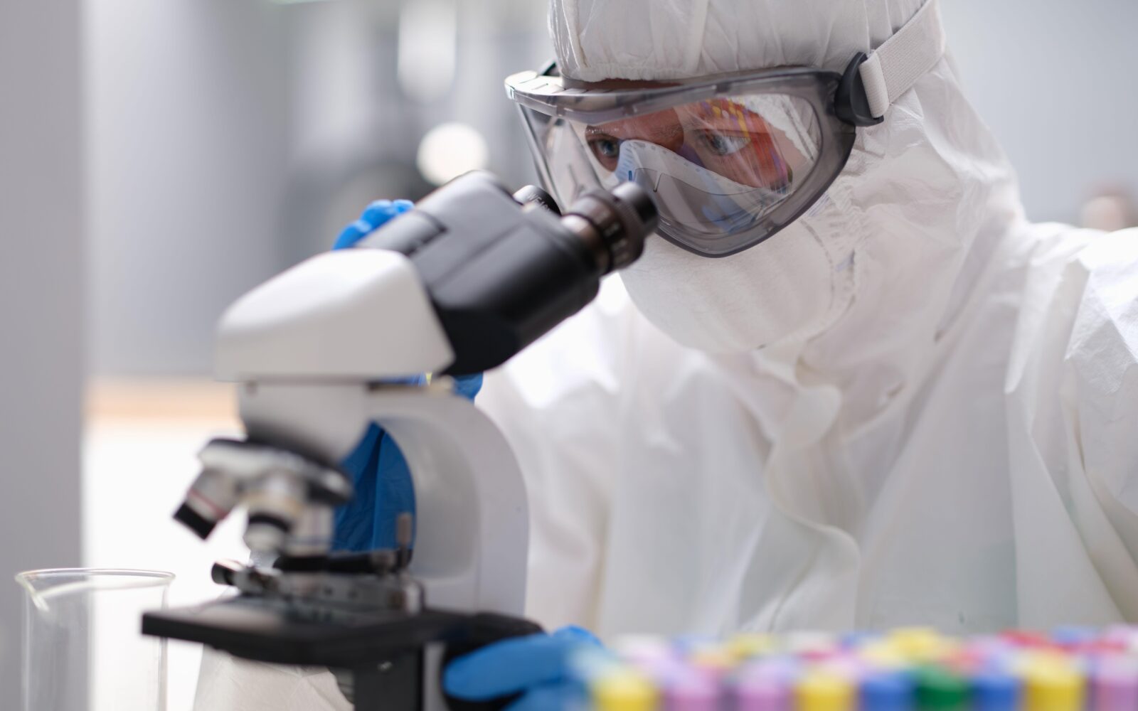 Raziskovalec v zaščitni protikužni obleki med laboratorijskim delom pri preučevanju povzročiteljev kuge