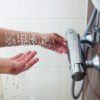 Ženska nastavlja temperaturo vode na tušu pred prhanjem