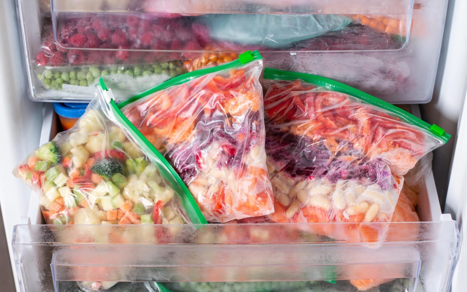 Zamrznjeno sadje in zelenjava v vrečkah v predalu zamrzovalnika.